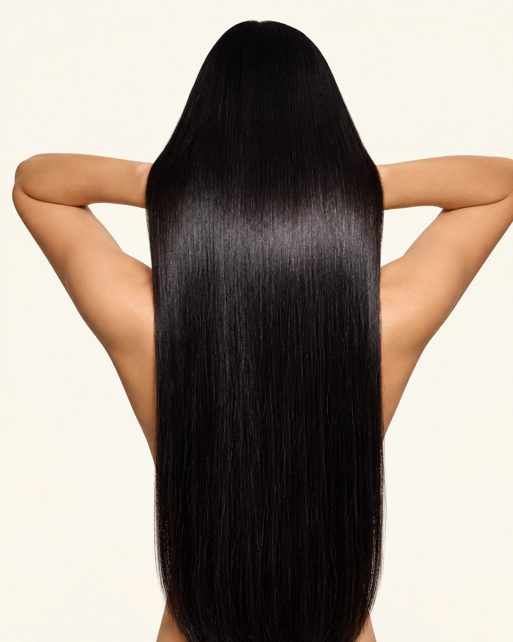 A woman seen from behind with very long straight black hair falling down her back and her arms raised behind her head