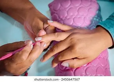 A nail technician gently shaping and buffing a client's fingernails during a manicure