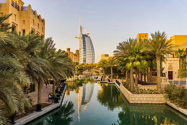 Burj Al Arab rising above a palm-lined Dubai canal at golden hour