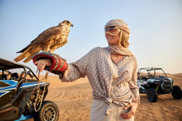 A traveler with a falcon in the Arabian Desert near Dubai